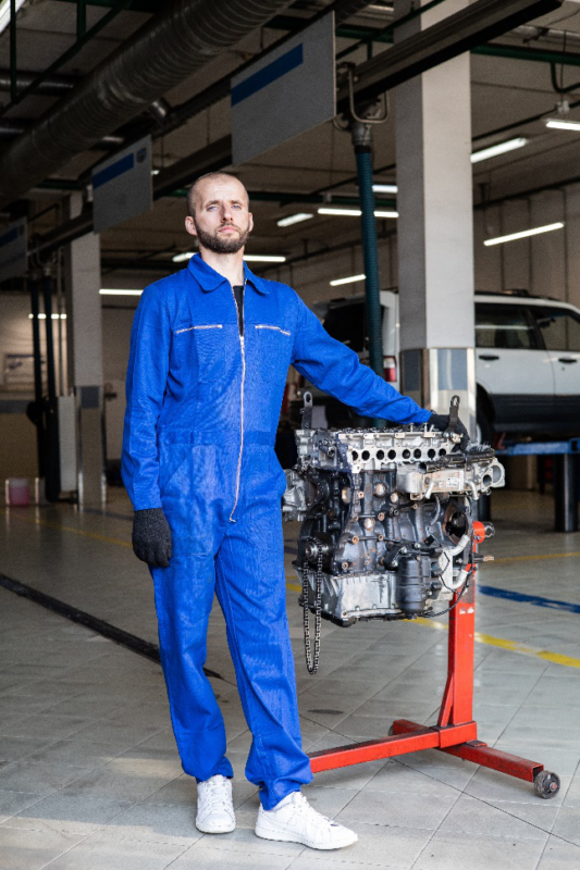  a man standing beside a car engine